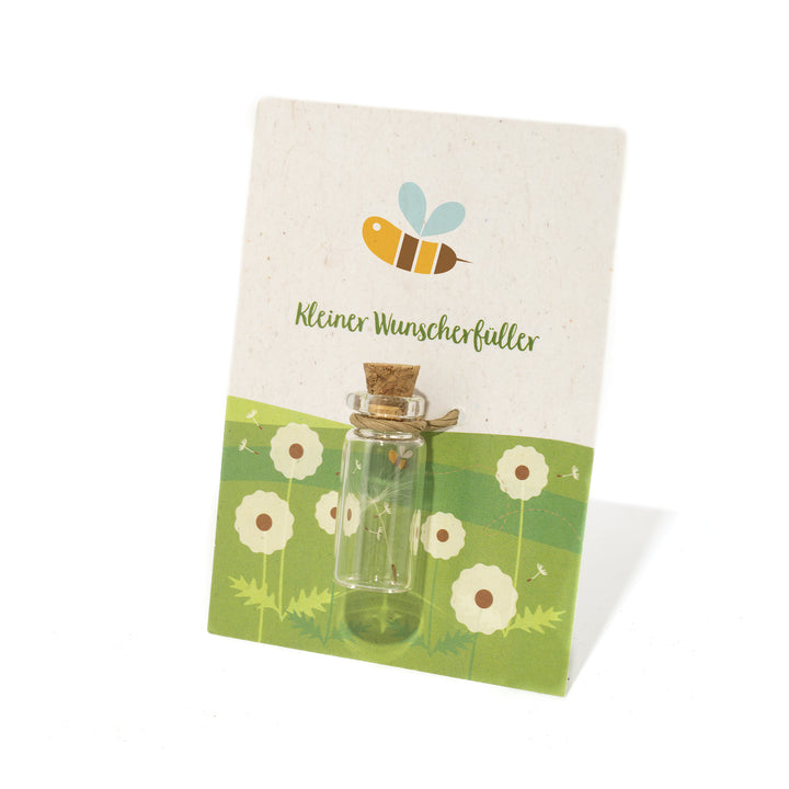 Petite bouteille en verre avec bouchon en liège sur une carte décorative avec un motif d'abeille et l'inscription "Little Wish Fulfiller".