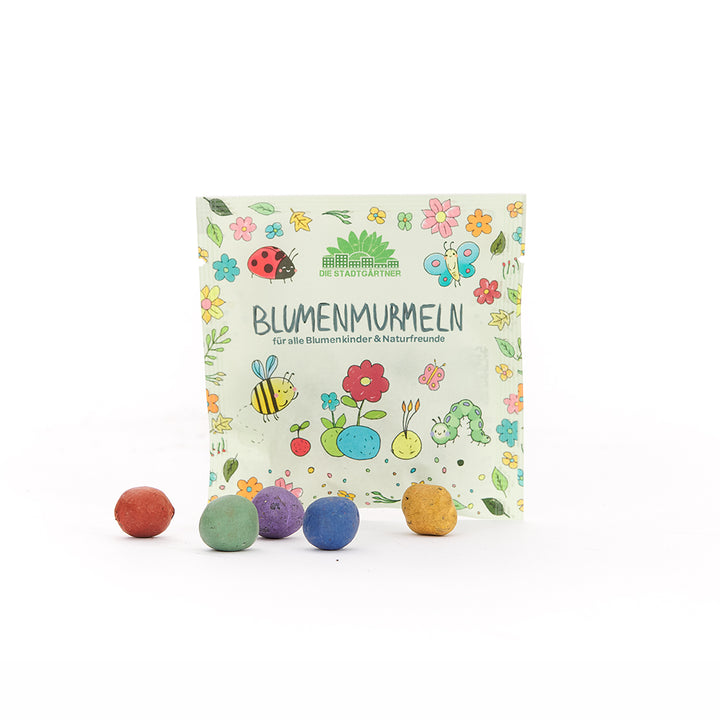 Emballage avec l'inscription "Flower Marbles" et des boules rondes colorées sur le devant ; l'emballage est illustré de fleurs colorées, d'insectes et d'animaux.