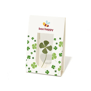Sac en papier avec un trèfle à quatre feuilles et le texte « bee happy » ainsi qu'une illustration d'abeille.