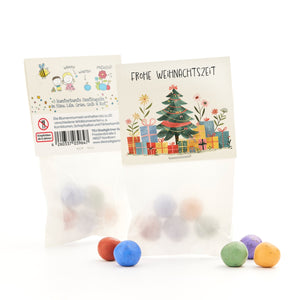 Emballage cadeau avec un motif de Noël et des boules de graines colorées en bleu, violet, vert, jaune et rouge.