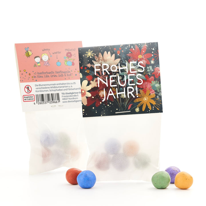 Deux sacs de boules de graines colorées, l'un avec un imprimé floral "Bonne année !" et l'autre avec des descriptions et des dessins, avec quelques boules posées devant.