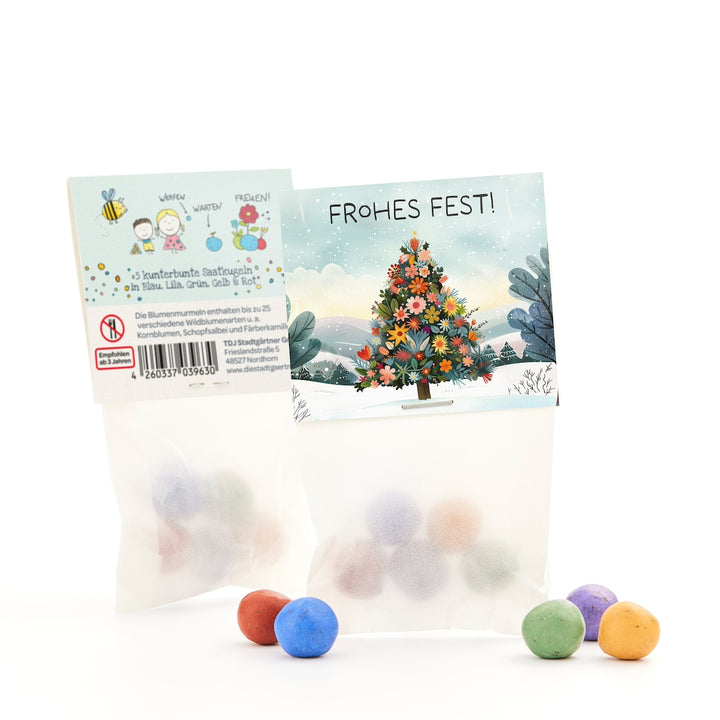Deux petits sacs de boules de graines colorées, l'un avec un sapin de Noël et un message « Joyeux Noël ! », avec diverses boules colorées devant.