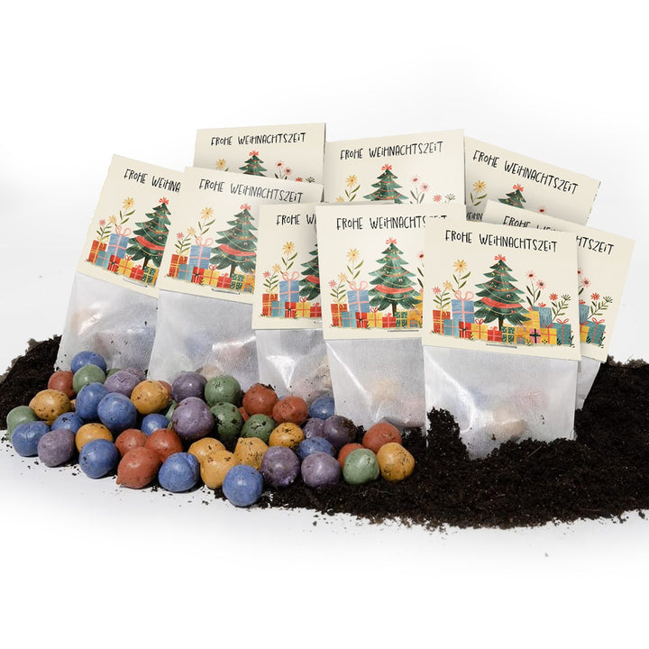 Plusieurs petits sacs de cartes de Noël avec l'inscription « Joyeux Noël », avec des bombes de graines colorées et de la terre au premier plan.