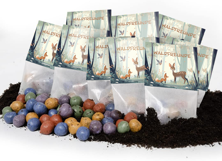 Derrière des boules de graines colorées sur le sol se trouvent plusieurs petits sacs étiquetés « WALDFREUNDE » (Amis de la forêt) et ornés d'illustrations d'animaux de la forêt.