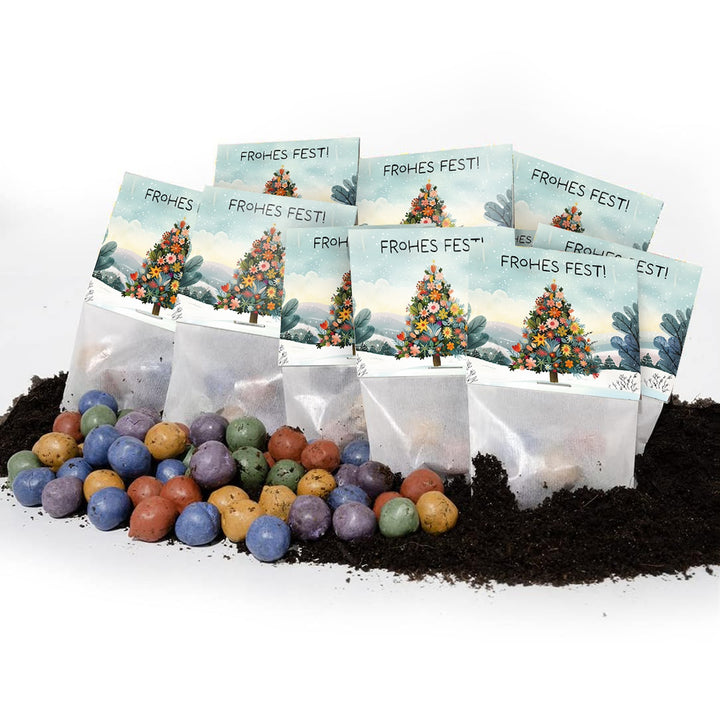 Plusieurs petits sacs avec l'inscription « Joyeuses fêtes ! » et un sapin décoré de Noël, devant lequel se trouvent des boules de graines colorées sur le sol.