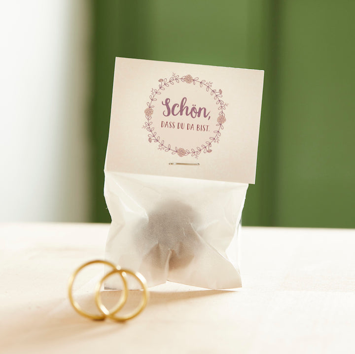 Petit sac avec l'inscription "C'est super que tu sois là" et deux alliances en or devant.
