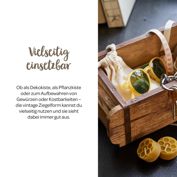 Boîte en bois de style vintage avec des lunettes de soleil, des clés, un sac en tissu et un mètre ruban sur une table, à côté de deux blocs de cire jaune.