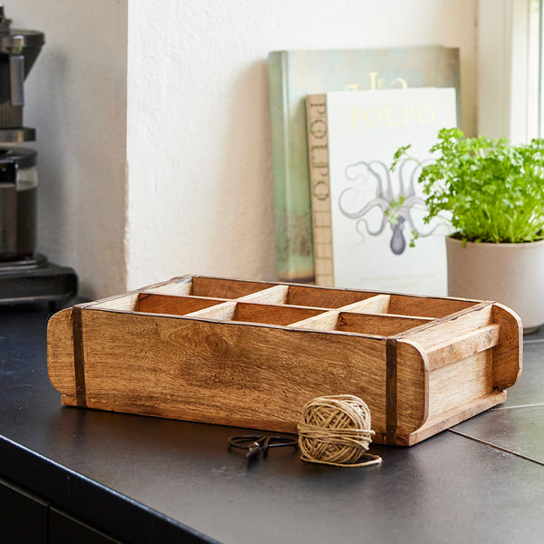 Boîte en bois sur un comptoir avec une pelote de laine et une plante en arrière-plan.