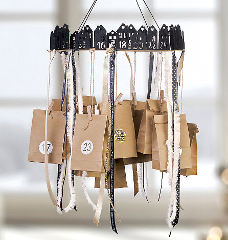 Calendrier de l'Avent fait maison réalisé à partir de sacs en papier brun suspendus à un cadre rond avec des maisons noires et des rubans.