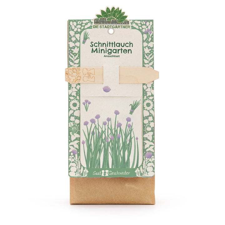 Sac en papier avec kit de culture de ciboulette, illustré de motifs végétaux verts et violets et d'une étiquette en bois, par Die Stadtgärtner.