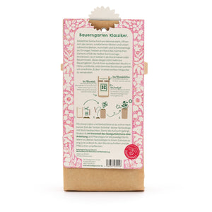 Dos d'un sachet de graines de fleurs, description et instructions en allemand, motif floral rose, un logo rouge du Seed Festival en bas.