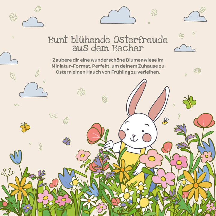 Illustration d'un lapin blanc dans une prairie colorée avec des fleurs printanières, des papillons et des nuages ; en haut se trouve un texte allemand sur la joie de Pâques et la décoration florale.