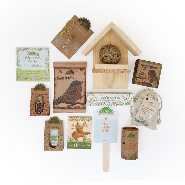 Divers produits de jardinage et naturels écologiques, dont des graines, des accessoires pour plantes, un nichoir avec de la nourriture et de petits articles cadeaux, disposés sur un fond blanc.