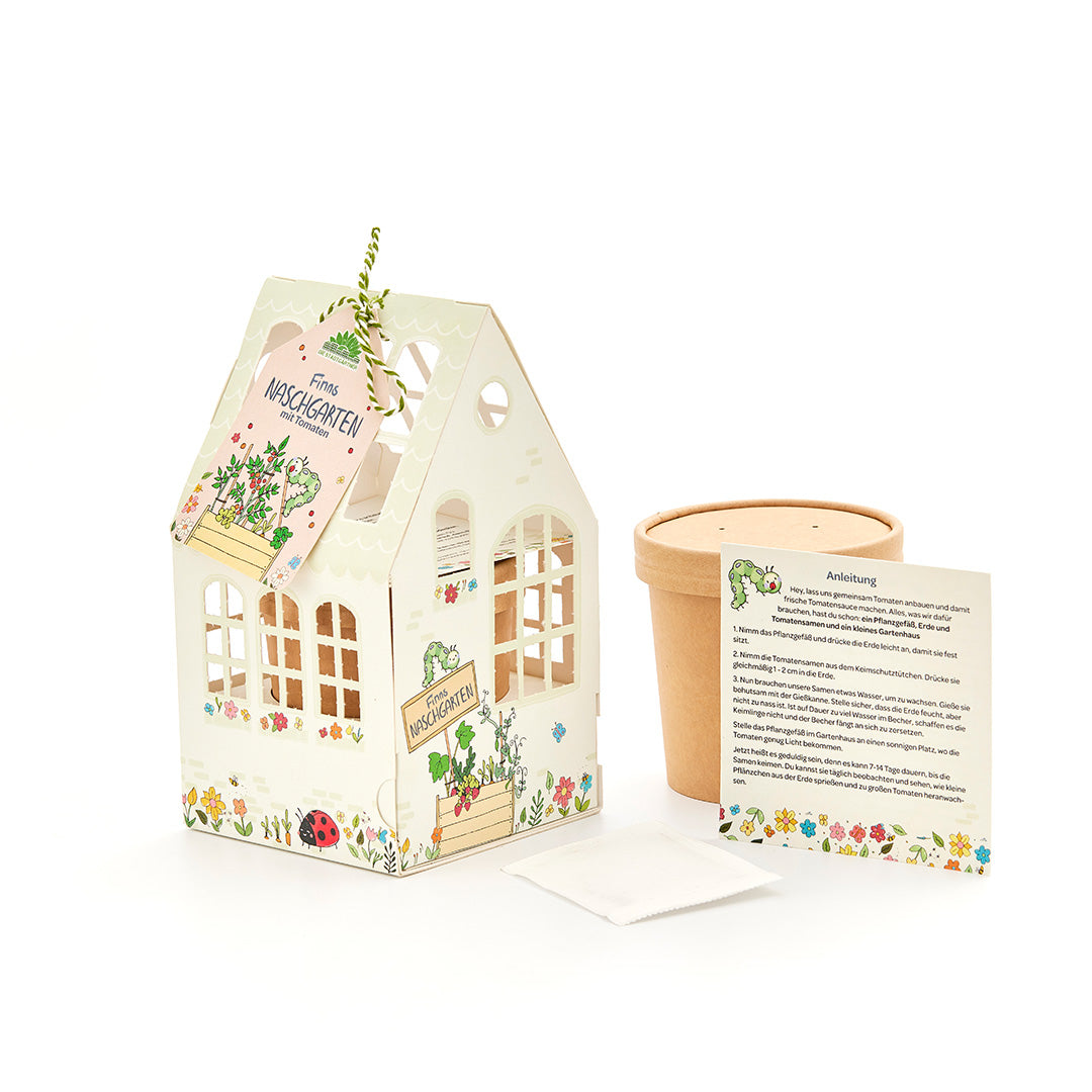 Coffret comprenant une petite serre décorative, un pot de fleurs, des instructions et un sachet de graines pour faire pousser des tomates.