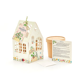 Coffret comprenant une petite serre décorative, un pot de fleurs, des instructions et un sachet de graines pour faire pousser des tomates.