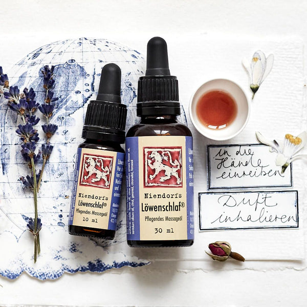 Huiles essentielles sur fond blanc avec brins de lavande, tasse à thé et notes manuscrites.