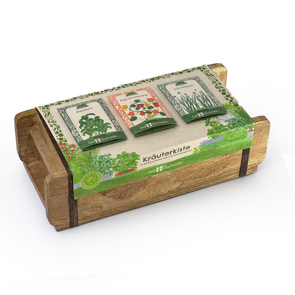 Coffret en bois avec trois sachets de graines d'herbes (basilic, capucine, ciboulette) et l'inscription "Kräuterkiste" (Boîte à herbes) sur une banderole.