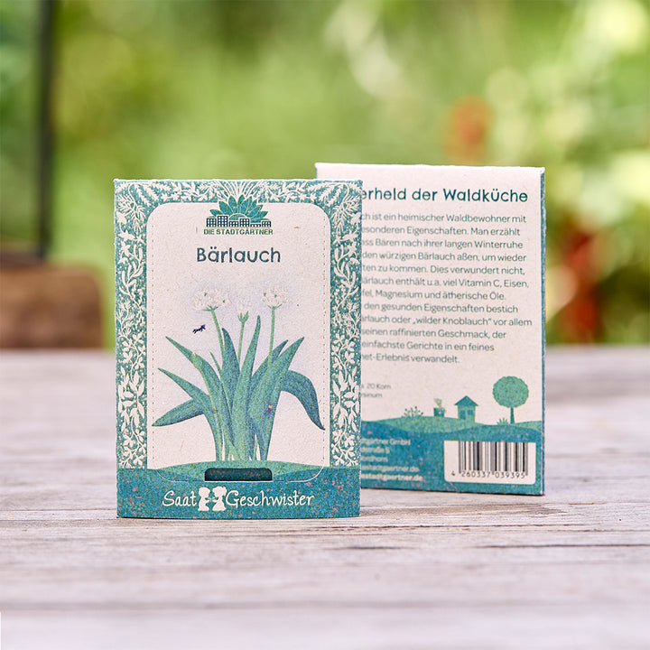 Deux sachets de graines d'ail des ours de "Die Stadtgärtner" avec illustration botanique, sur une table en bois à l'extérieur.