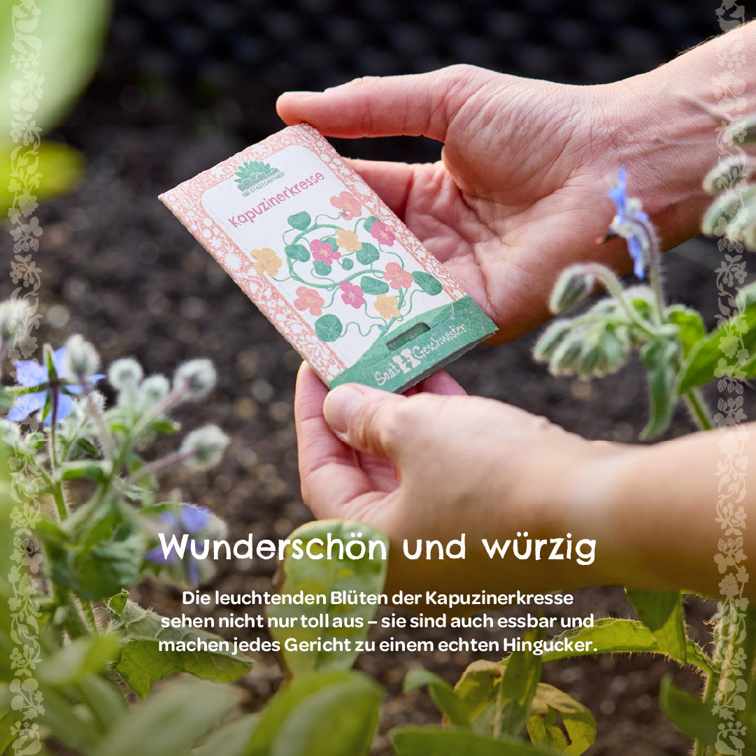 Mains tenant un sachet de graines étiqueté « capucine » dans le jardin, avec des plantes à fleurs à côté.