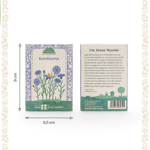 Deux sachets de graines de bleuet avec illustration florale et description du produit en allemand, ainsi que des dimensions de 9 cm de haut et 6,5 cm de large.