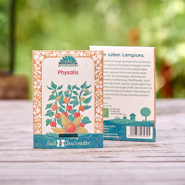 Deux sachets de graines de Physalis de la marque "Die Stadtgärtner" se trouvent sur une table en bois, avec une plante illustrée sur le devant et du texte au dos.