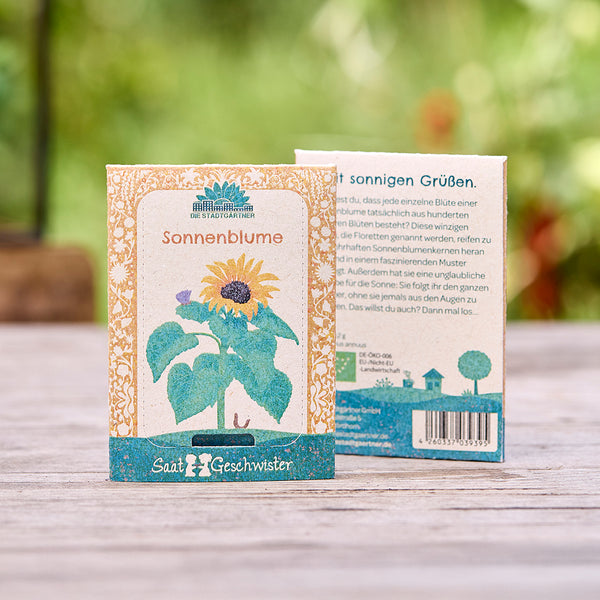 Deux paquets de graines de tournesol de la marque "Die Stadtgärtner" sur une table en bois, recto et verso visibles, avec une illustration d'un tournesol.