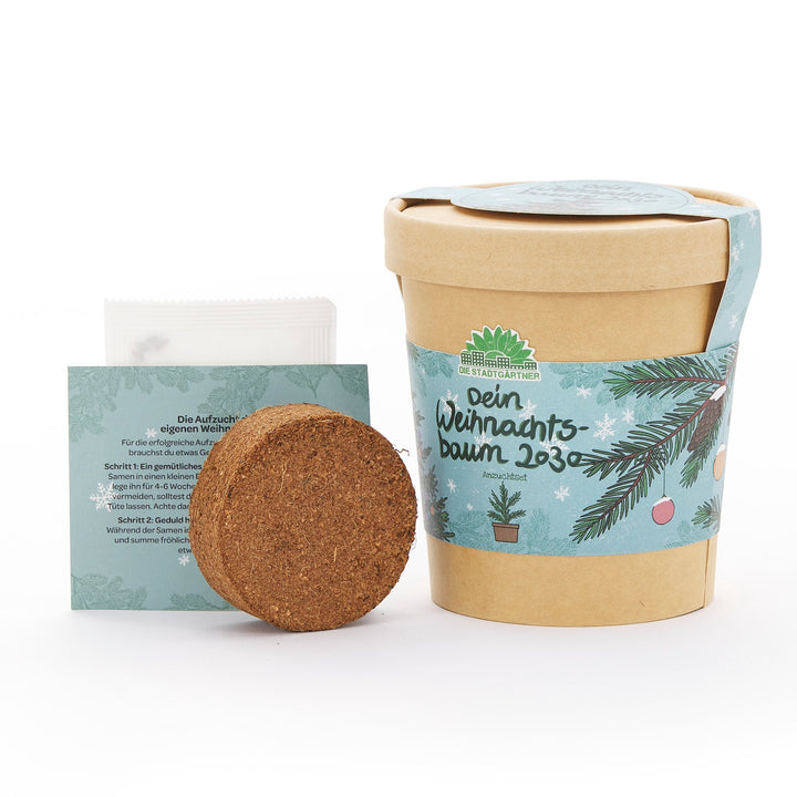 Kit de culture pour sapin de Noël, composé d'un pot de fleurs marron avec une bannière de Noël, d'une tablette de terreau et d'instructions en allemand.