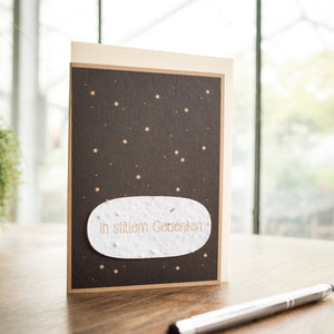 Une carte de condoléances avec l'inscription « En souvenir silencieux » et un motif d'étoile se trouve sur une table à côté d'un stylo.