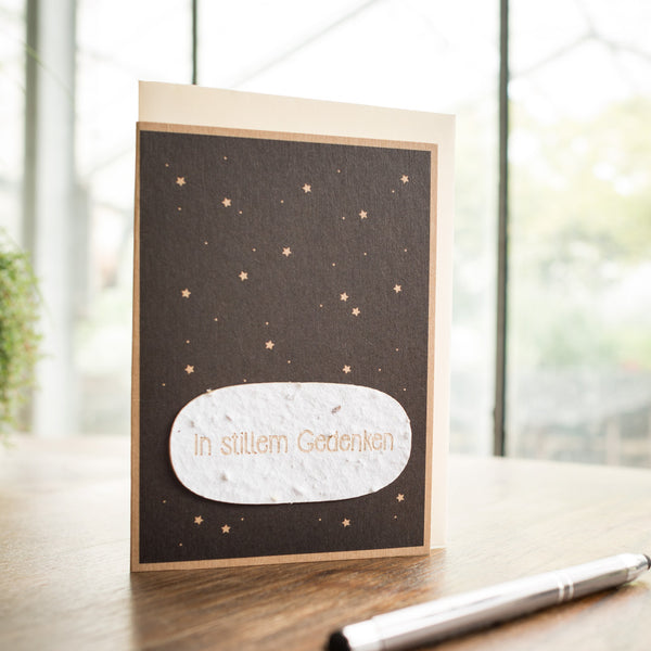 Une carte de condoléances avec l'inscription « En souvenir silencieux » et un motif d'étoile se trouve sur une table à côté d'un stylo.