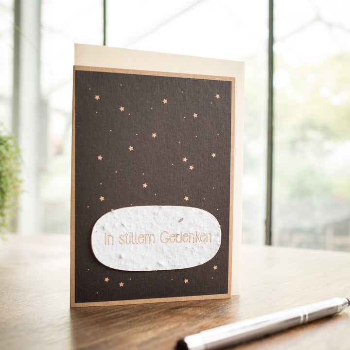 Une carte de condoléances avec l'inscription « En souvenir silencieux » et un motif d'étoile se trouve sur une table à côté d'un stylo.