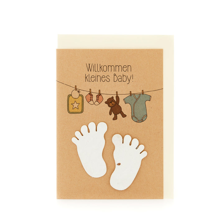 Carte de félicitations de naissance avec l'inscription "Bienvenue petit bébé", les pieds de bébé et les vêtements de bébé suspendus.