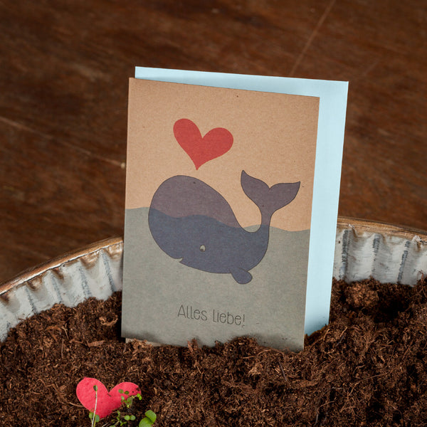 Carte de vœux avec une baleine dessinée, un cœur rouge et le texte « Tous mes meilleurs vœux ! » debout sur terre.