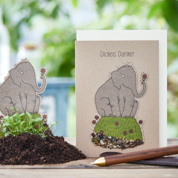 Carte de vœux avec un mammouth dessiné avec l'inscription « Un grand merci ! », à côté de la terre et des semis verts.