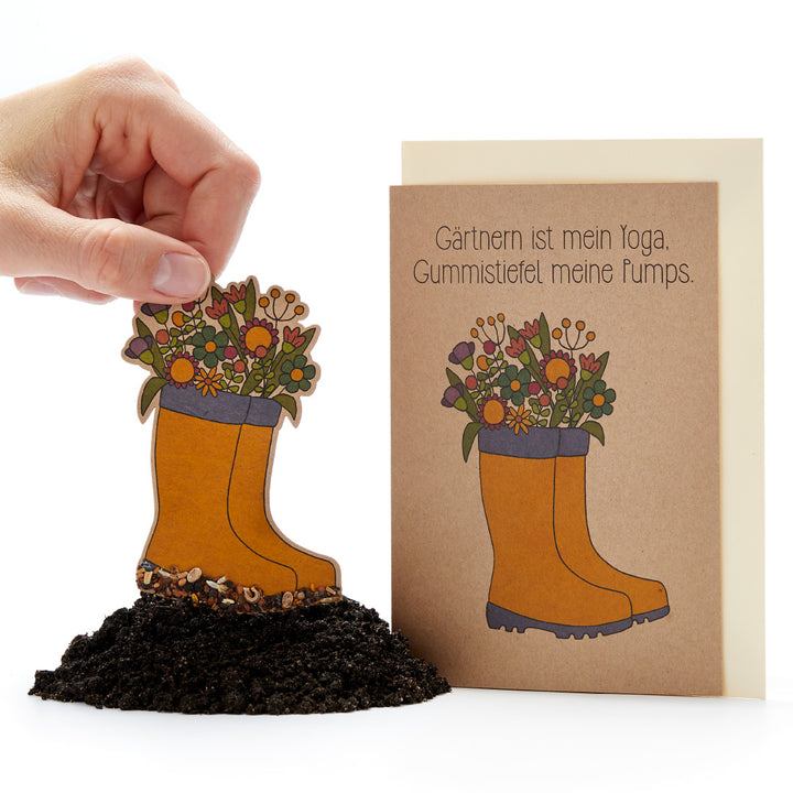 Une composition florale en forme de bottes en caoutchouc, à côté une carte avec l'inscription « Le jardinage est mon yoga, les bottes en caoutchouc sont mes escarpins ».
