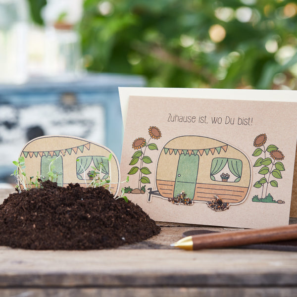 Carte de vœux dessinée à la main avec un camping-car et des fleurs à côté d'une pelle et de terre.