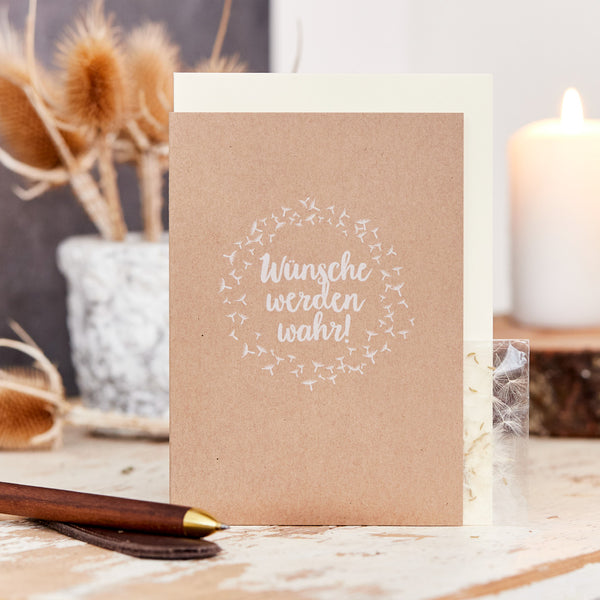 Carte de vœux avec l'inscription "Les souhaits se réalisent !" sur une table à côté d'un stylo-plume et d'éléments décoratifs.