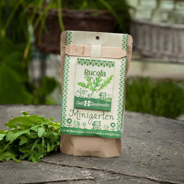 Emballage de graines de roquette à côté de feuilles de roquette fraîches sur un fond de pierre.