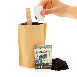 Une main tenant un sac de graines au-dessus d'un sac en papier rempli de terre, à côté d'un panneau indiquant « Le jardin de Satan » et d'un autre sac de graines.