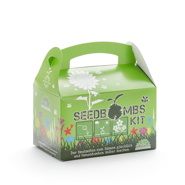 Emballage vert d'un kit de bombes à graines avec un imprimé de fleurs et le slogan « Le kit pour rendre les abeilles heureuses et fabriquer soi-même des bombes à graines ».