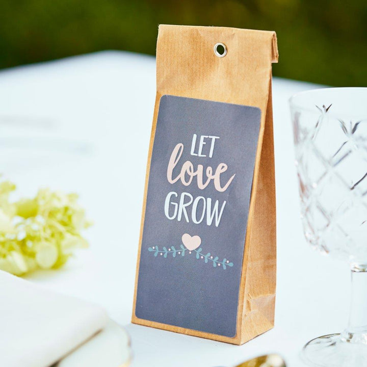 Sac en papier brun avec les mots « Laissez l'amour grandir » et une décoration en forme de cœur sur une table dressée de manière festive.