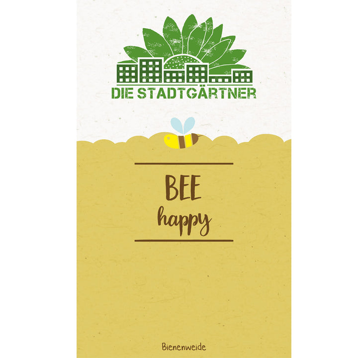 Illustration avec le texte "DIE STADTGÄRTNER BEE happy" et l'image d'une abeille au-dessus d'une prairie fleurie stylisée, avec des maisons et des arbres en arrière-plan.