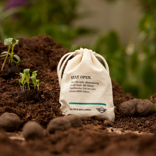 Sac en tissu avec inscription sur le sol, jeunes plantes en arrière-plan.