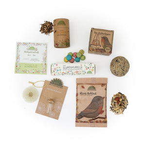 Divers produits de jardin et mélanges de graines pour fleurs sauvages, thé biologique et graines pour oiseaux disposés sur un fond blanc"