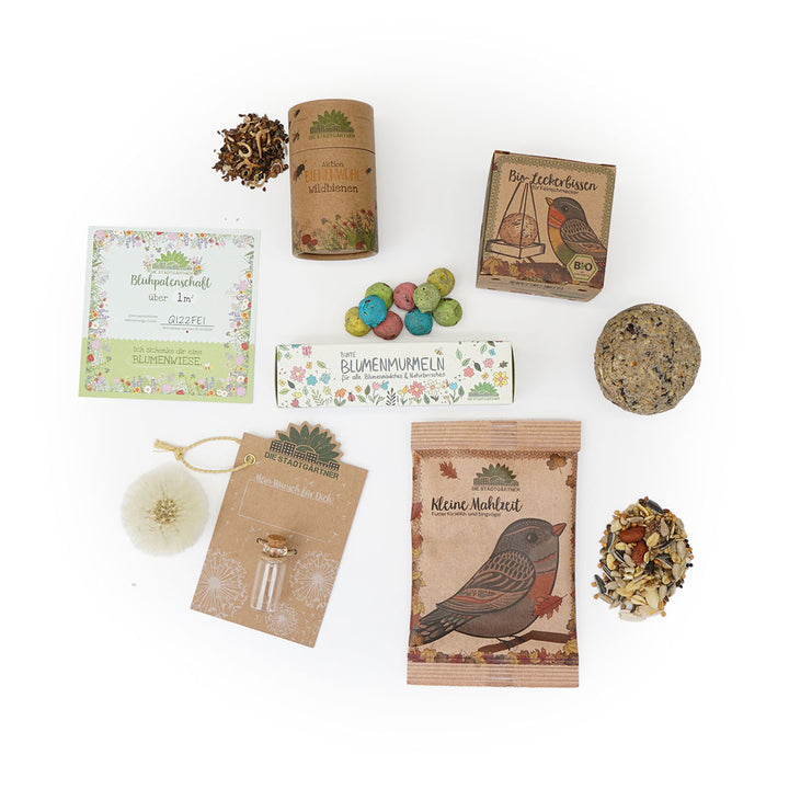 Divers produits de jardin et mélanges de graines pour fleurs sauvages, thé biologique et graines pour oiseaux disposés sur un fond blanc"