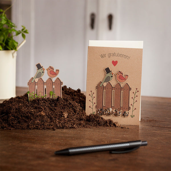 Carte de voeux sur terre avec des illustrations d'oiseaux, de petites plantes et le texte "Félicitations !".
