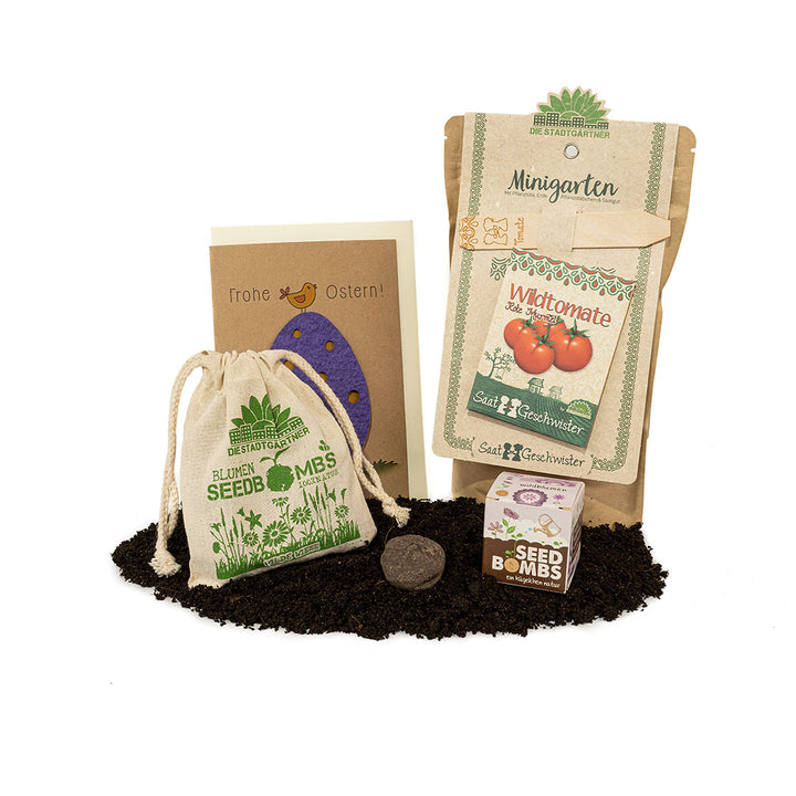Ensemble de jardin avec sachets de graines, bombes de graines, carte de Pâques et sac de jute sur terre.
